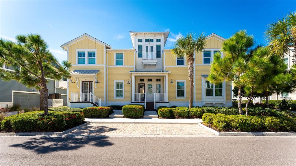 A yellow two-story house with a white porch, balcony, and landscaped front yard — 280 SAINT LUCIA DRIVE UNIT 101, BRADENTON, FL