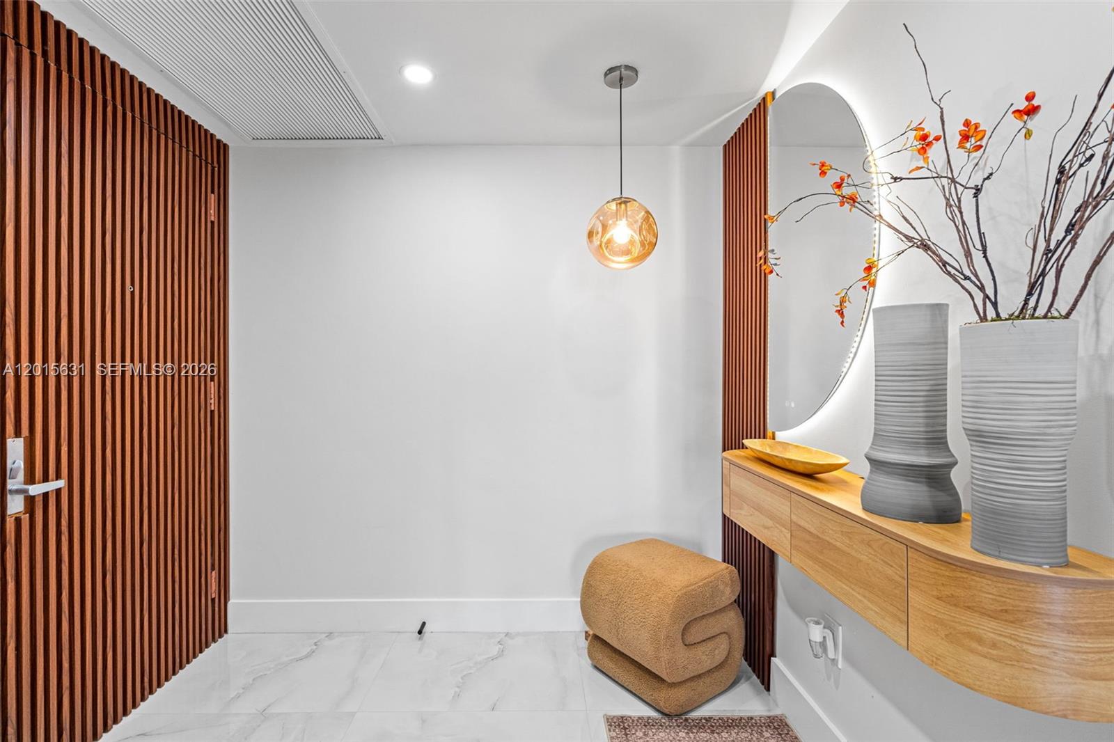 A modern entryway features a wood-slatted wall, a floating console table, and a round mirror — 465 Brickell Ave # 3301, Miami FL 33131, MIAMI, FL