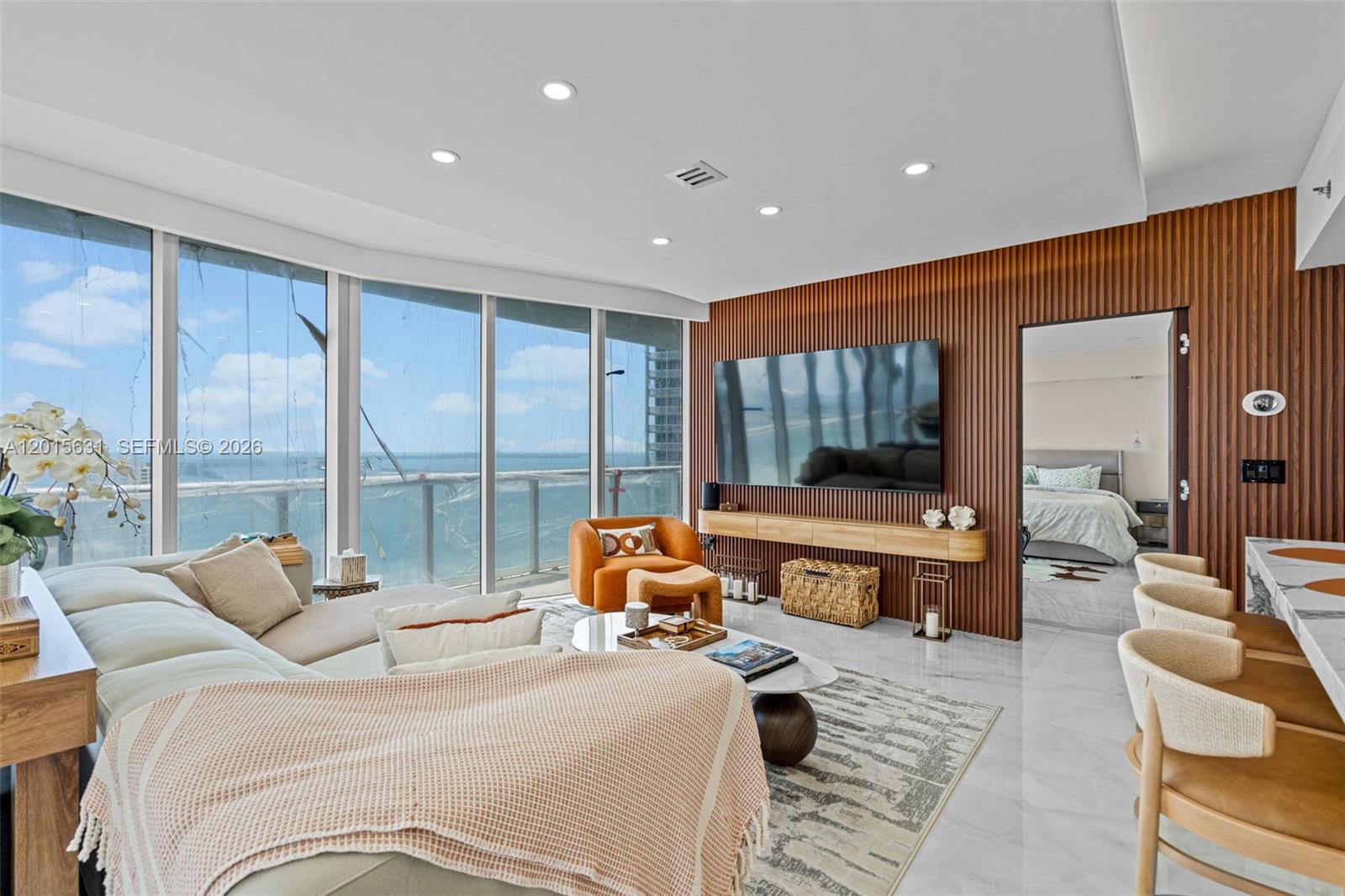 A modern living room features floor-to-ceiling windows, a wood-slatted accent wall, and ocean views — 465 Brickell Ave # 3301, Miami FL 33131, MIAMI, FL