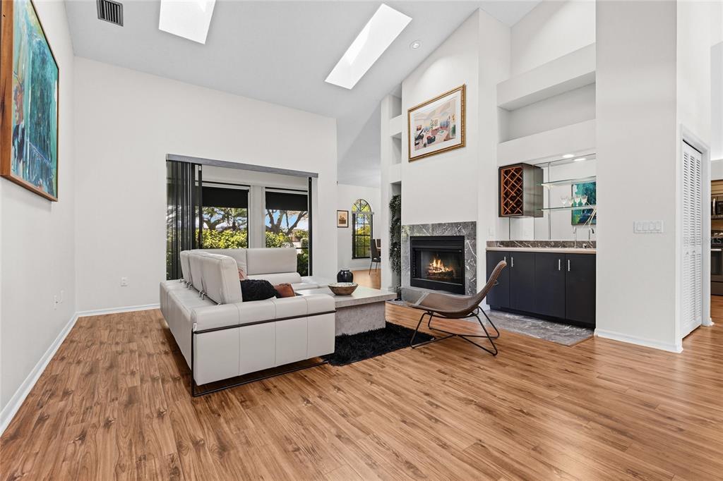 A living room features wood-look flooring, a white sofa, a fireplace, and a wet bar — 4531 LAS BRISAS LANE, SARASOTA, FL