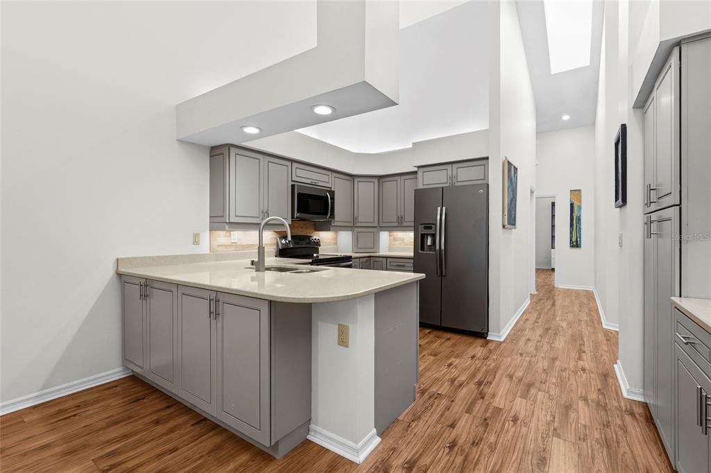 A kitchen features gray cabinets, stainless steel appliances, and a peninsula with a light countertop — 4531 LAS BRISAS LANE, SARASOTA, FL