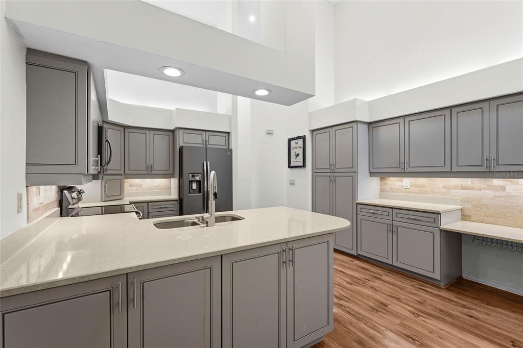 A kitchen features gray cabinets, light countertops, a central island, and wood-look flooring — 4531 LAS BRISAS LANE, SARASOTA, FL