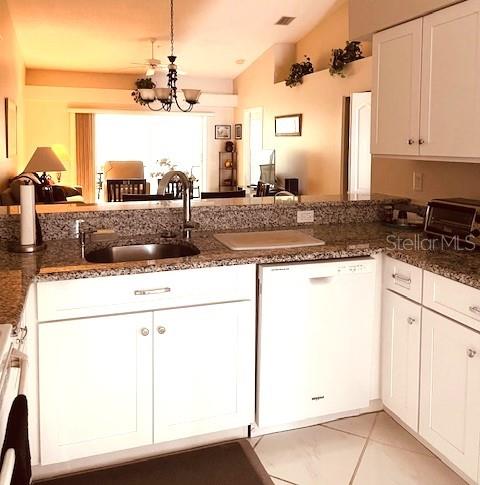 A kitchen with white cabinets, granite countertops, and a view into the living area — 9480 HIGH GATE DRIVE UNIT 2125, SARASOTA, FL