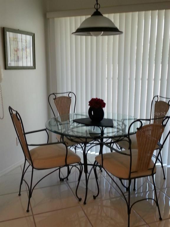 A dining area features a glass-topped table with four wicker-backed chairs and a pendant light — 9480 HIGH GATE DRIVE UNIT 2125, SARASOTA, FL