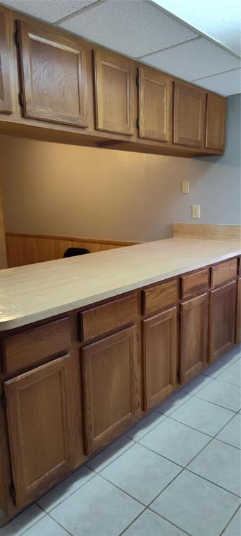 A kitchen features oak cabinets, a light-colored laminate countertop, and white tile flooring — 2811 SW ARCHER ROAD UNIT F46, GAINESVILLE, FL
