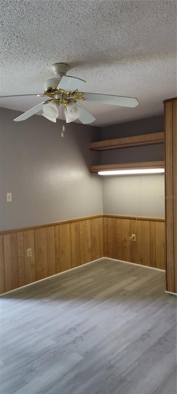 A room with wood paneling, light-colored flooring, a ceiling fan, and built-in wall shelving — 2811 SW ARCHER ROAD UNIT F46, GAINESVILLE, FL