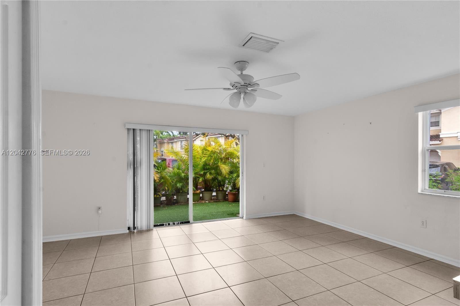 An empty room features light-colored tile flooring, a ceiling fan, and sliding glass patio doors — 12990 SW 30th Ct # 150, Miramar FL 33027, MIRAMAR, FL