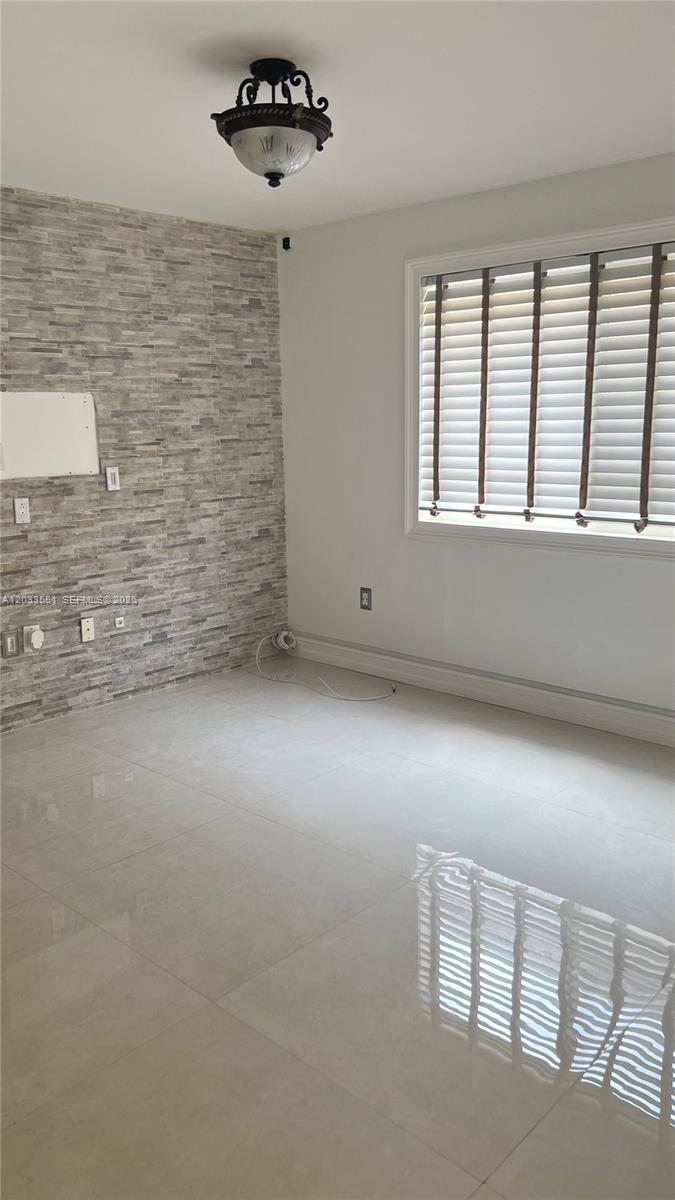 A room with light-colored tile flooring, a stone-accented wall, and a window with blinds — 6225 Kendale Lakes Cir # 263, Miami FL 33183, MIAMI, FL