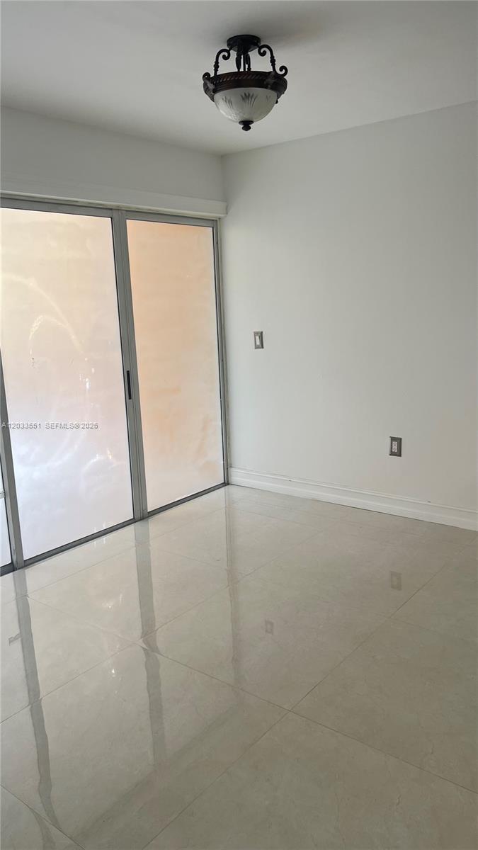 A room with light-colored tile flooring, white walls, a ceiling light fixture, and sliding glass doors — 6225 Kendale Lakes Cir # 263, Miami FL 33183, MIAMI, FL