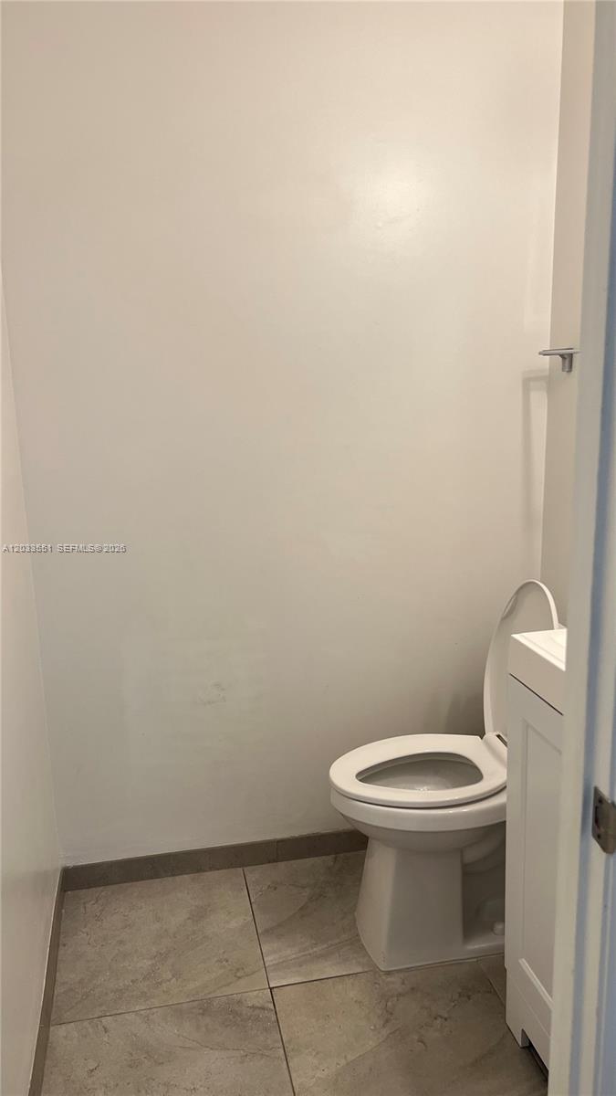 A small bathroom features a white toilet, a vanity, and light-colored floor tiles — 6225 Kendale Lakes Cir # 263, Miami FL 33183, MIAMI, FL