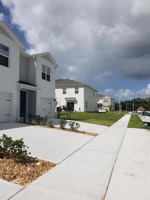 A row of modern white townhouses with concrete driveways and sidewalks under a cloudy sky — 1670 ROCK ELM ROAD, DAVENPORT, FL