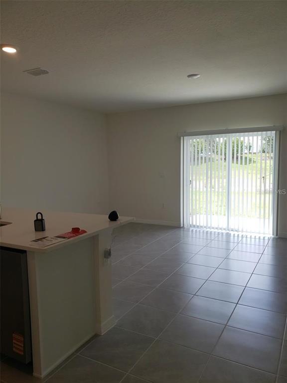 A kitchen island with a white countertop overlooks a tiled living area with sliding doors — 1670 ROCK ELM ROAD, DAVENPORT, FL