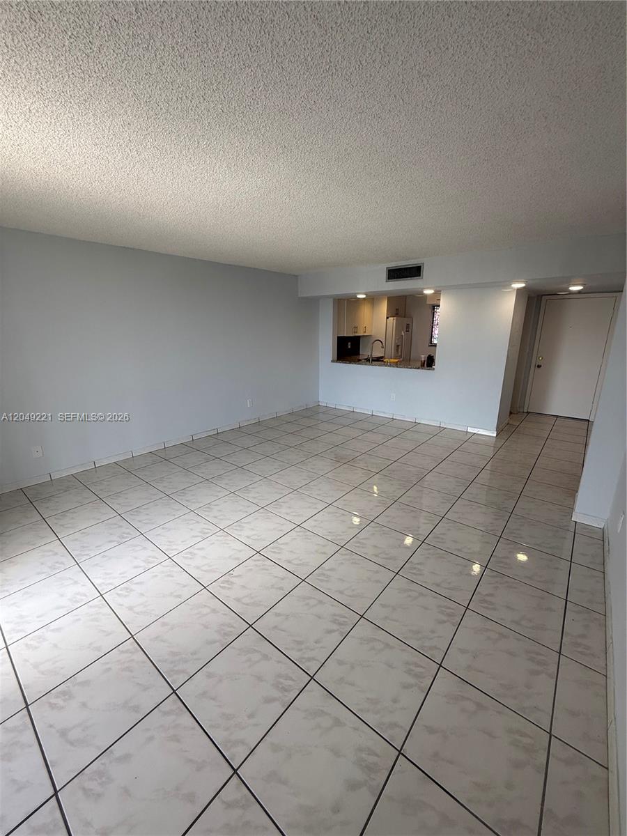 An open-concept living area features light-colored tile flooring and a pass-through window to the kitchen — 8625 NW 8th St # 420, Miami FL 33126, MIAMI, FL