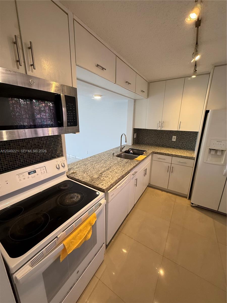 A kitchen features white cabinets, granite countertops, a glass-top stove, and a tile backsplash — 8625 NW 8th St # 420, Miami FL 33126, MIAMI, FL