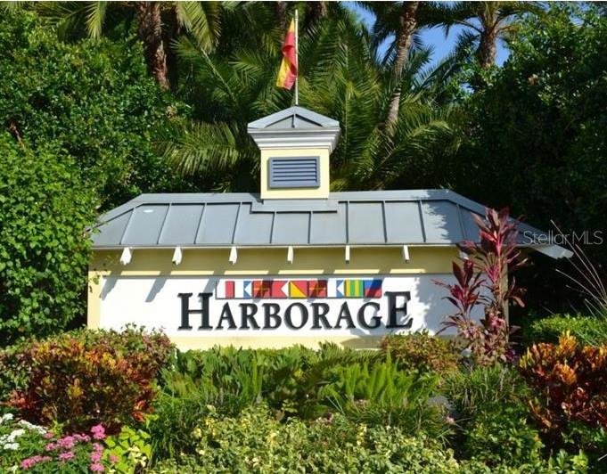 A sign for The Harborage stands in front of lush tropical landscaping and palm trees — 5647 KEY LARGO COURT UNIT C-07, BRADENTON, FL