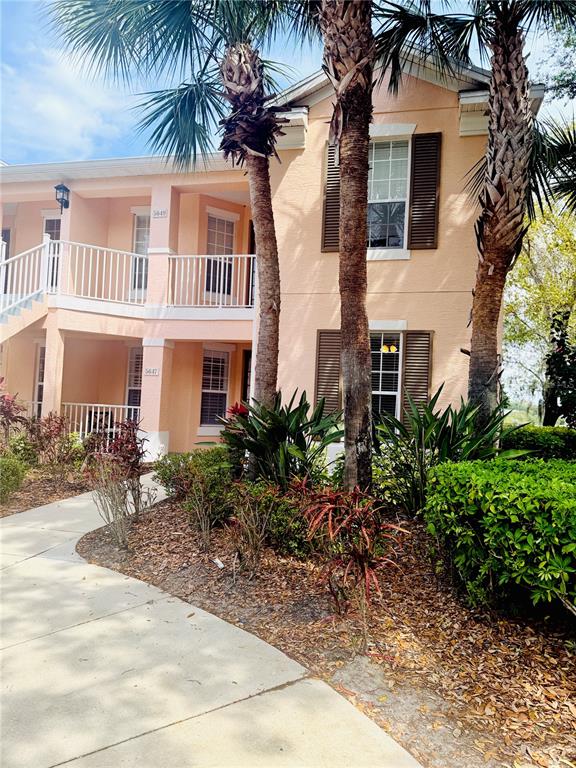 A two-story peach-colored apartment building features white railings, brown shutters, and palm trees — 5647 KEY LARGO COURT UNIT C-07, BRADENTON, FL