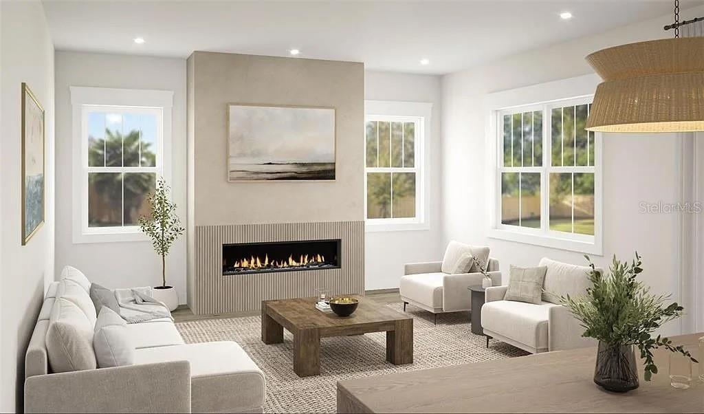 This rendering shows a living room with a linear fireplace, neutral furniture, and large windows — 8151 36TH AVENUE N, ST PETERSBURG, FL