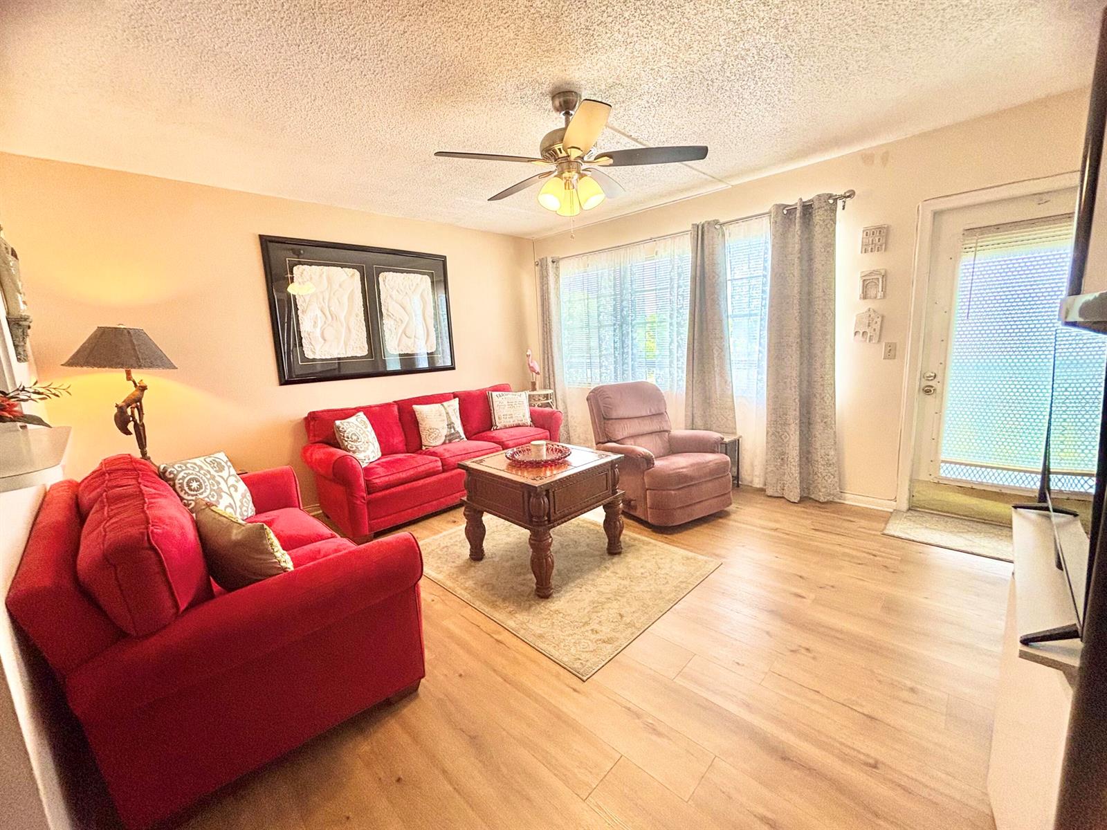 A living room features two red sofas, a recliner, a coffee table, and wood flooring — 4010 Harwood C # 4010, Deerfield Beach FL 33442, DEERFIELD BEACH, FL