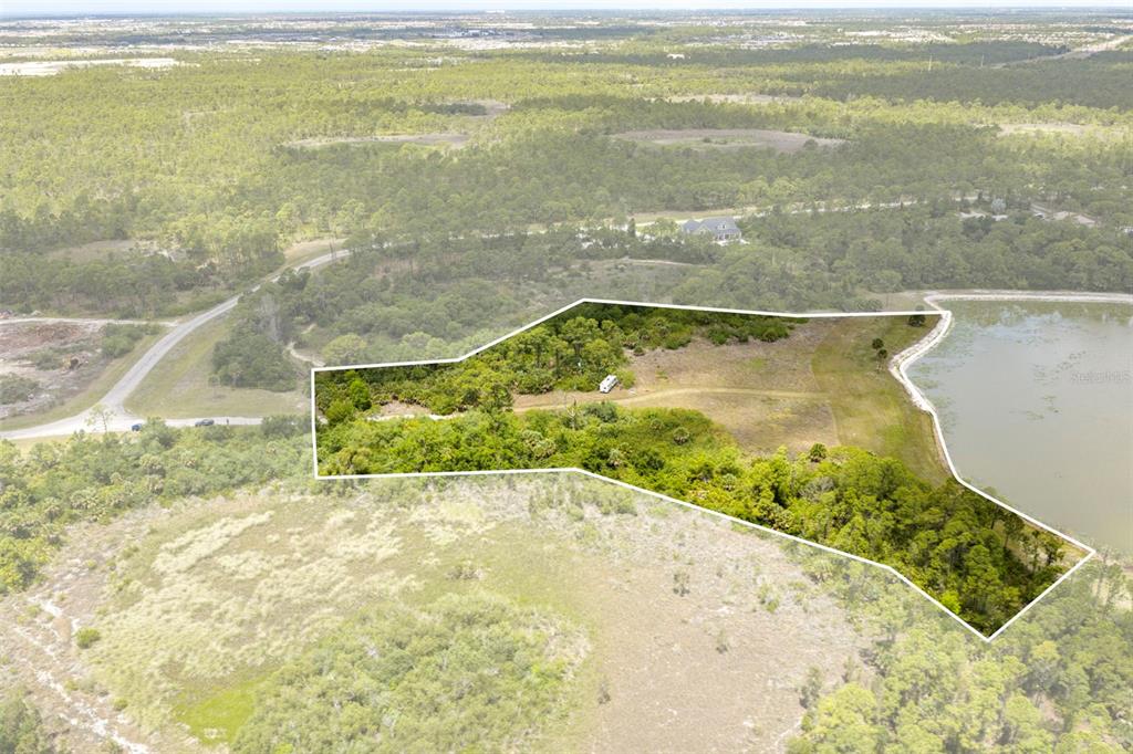 An aerial view shows a large, wooded plot of land bordering a lake — FALCON COURT, VENICE, FL