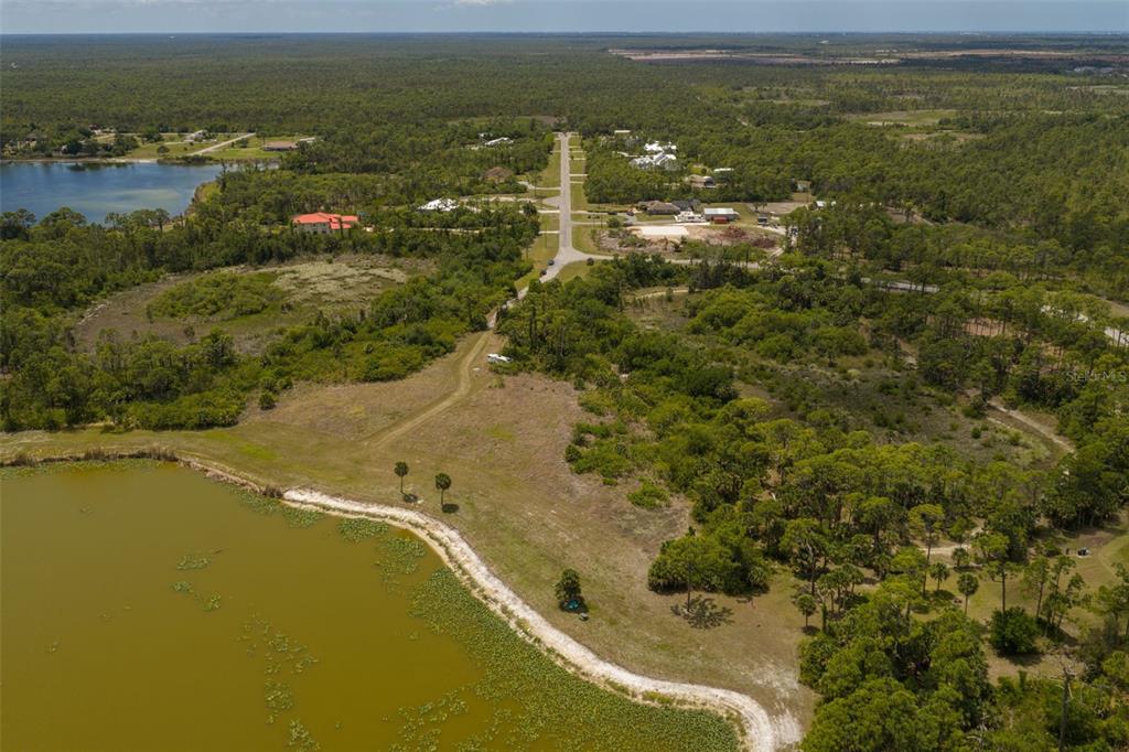 An aerial view shows a rural residential area with a large pond and wooded lots — FALCON COURT, VENICE, FL