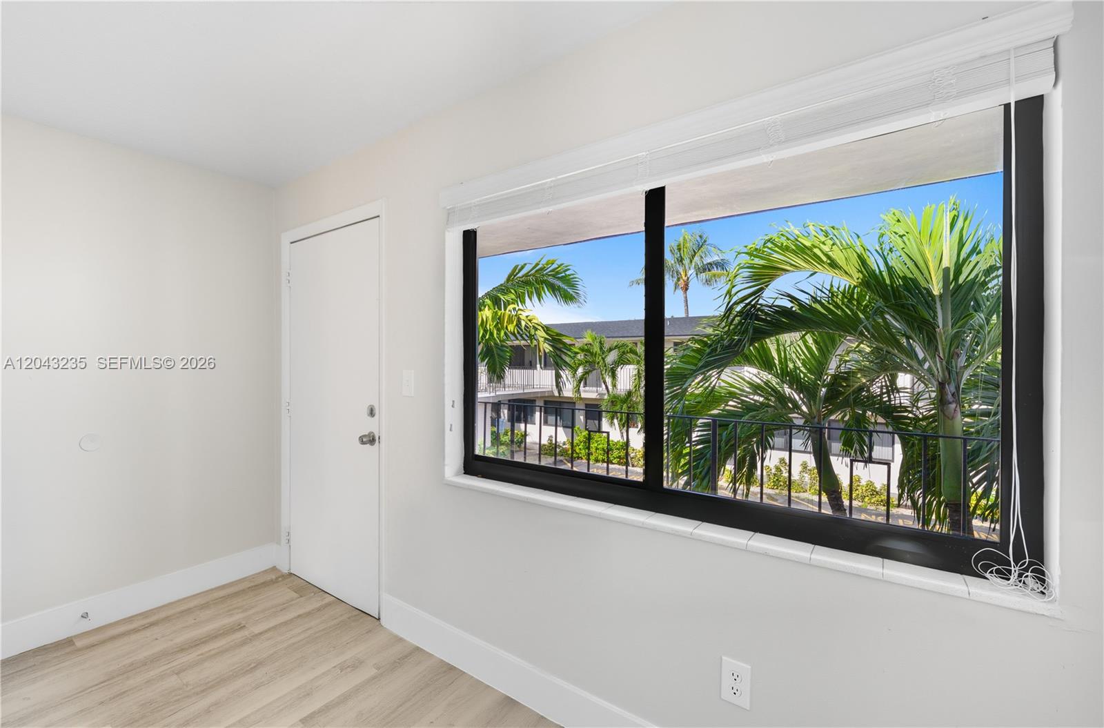 A room with light-colored walls, wood-look flooring, a white door, and a large window — 1310 W 29th St # 40, Hialeah FL 33012, HIALEAH, FL