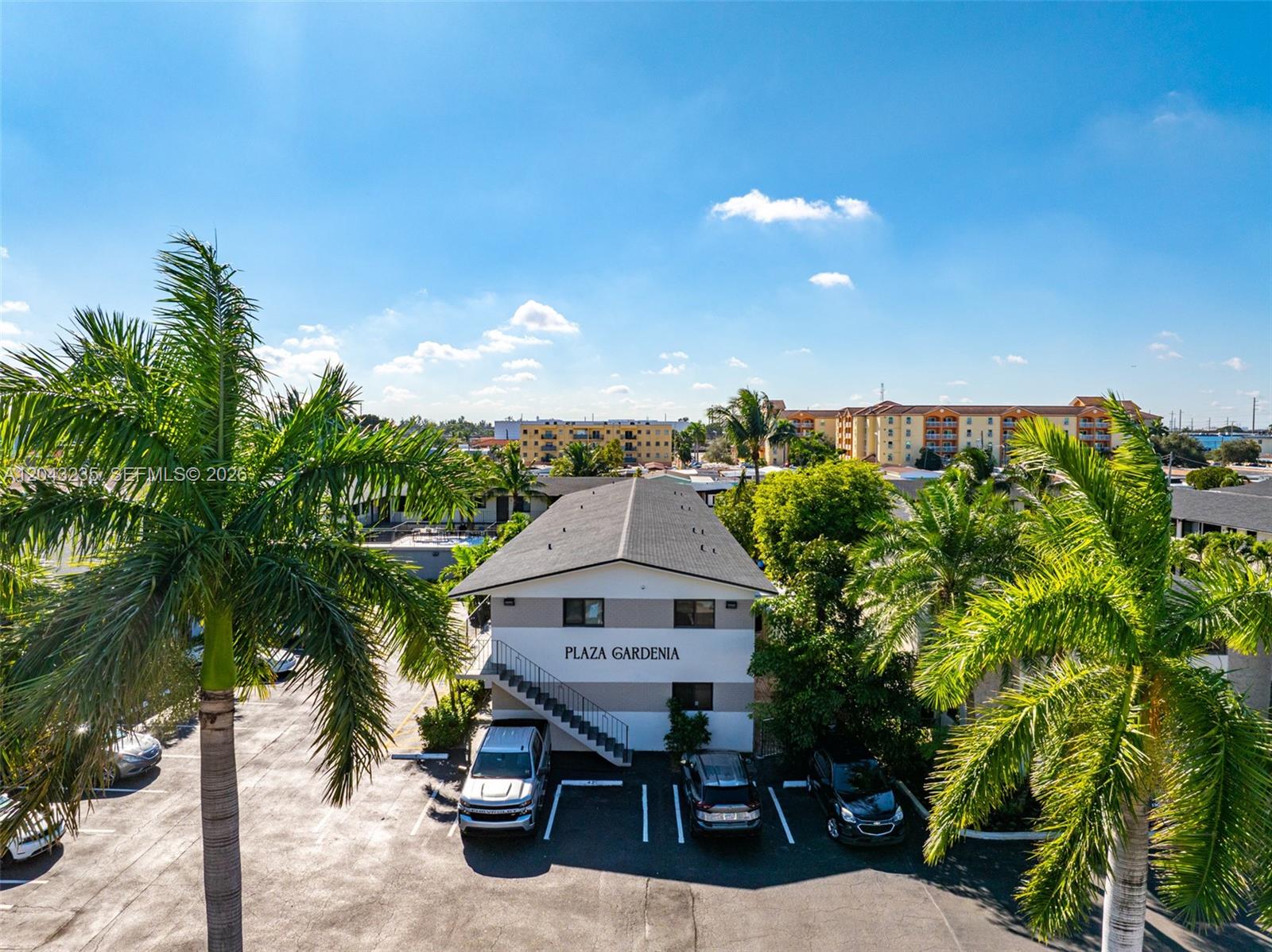 An aerial view shows the Plaza Gardenia apartment building with a parking lot and palm trees — 1310 W 29th St # 40, Hialeah FL 33012, HIALEAH, FL