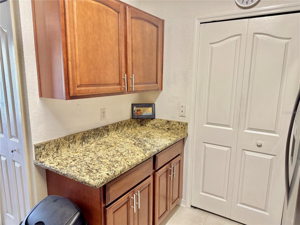 A kitchen area features wood cabinets, granite countertops, and a white double-door closet — 8828 DUNES COURT UNIT 12 304, KISSIMMEE, FL