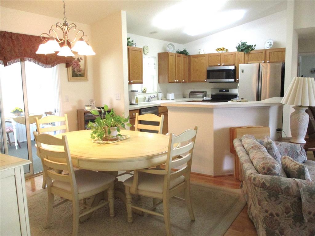 A dining area with a round table sits adjacent to an open kitchen with oak cabinets — 11588 SW 139TH PLACE, DUNNELLON, FL