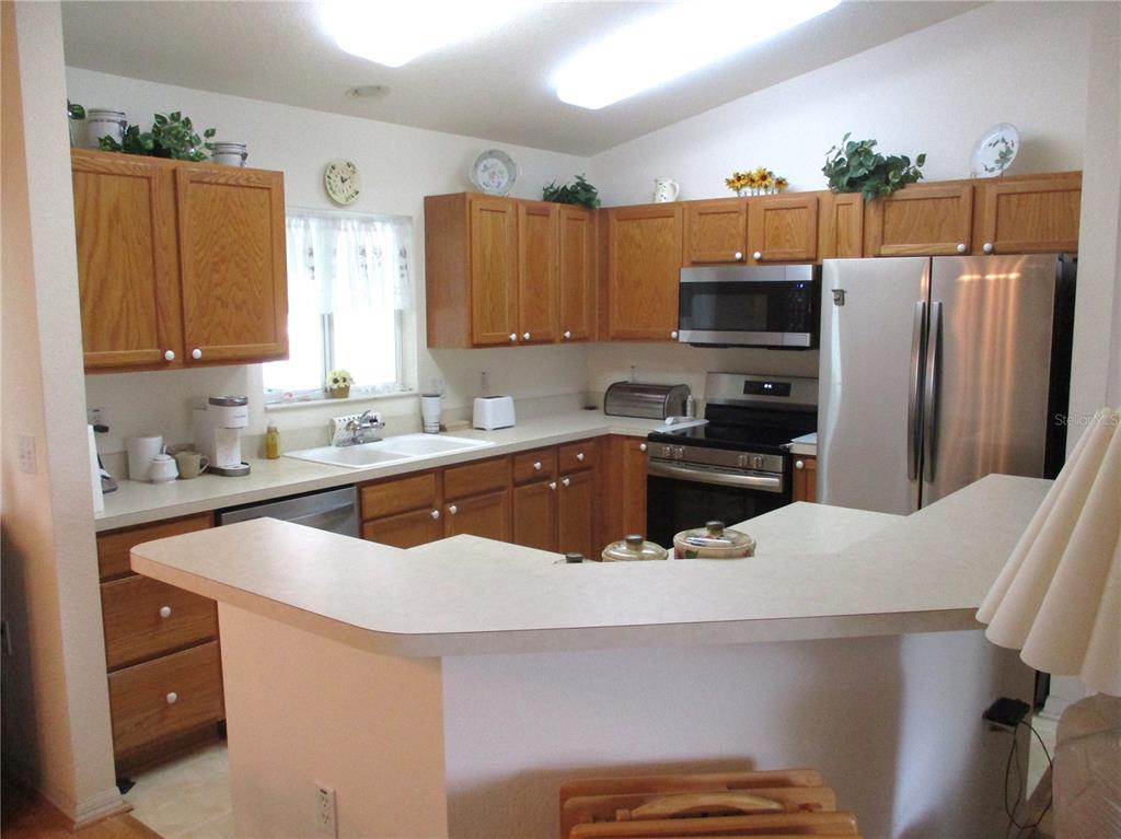 A kitchen features oak cabinets, laminate countertops, stainless steel appliances, and a breakfast bar — 11588 SW 139TH PLACE, DUNNELLON, FL