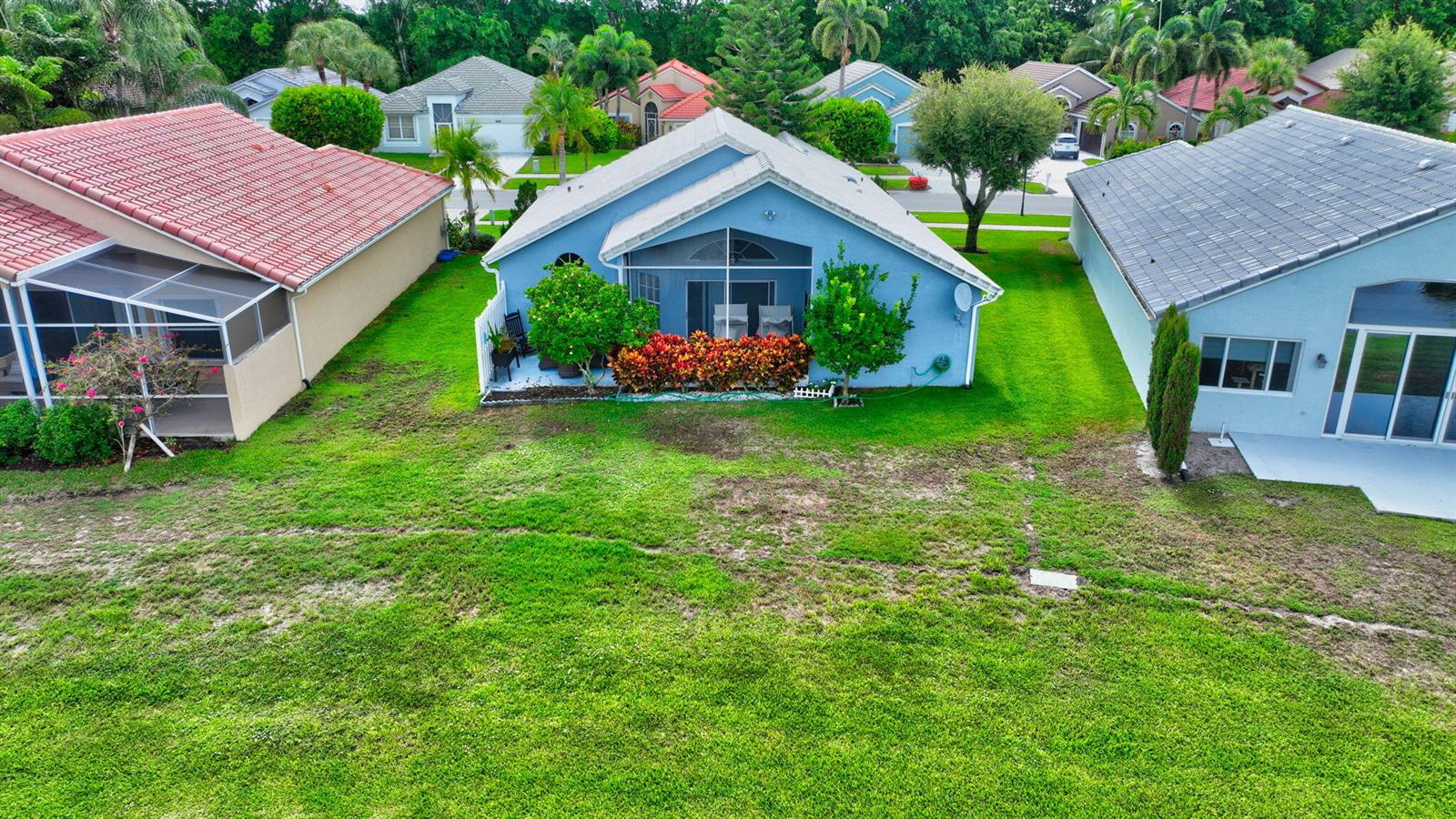 An aerial view of a blue house with a screened-in patio and a large lawn — 7777 Stirling Bridge Boulevard S, Delray Beach FL 33446, DELRAY BEACH, FL