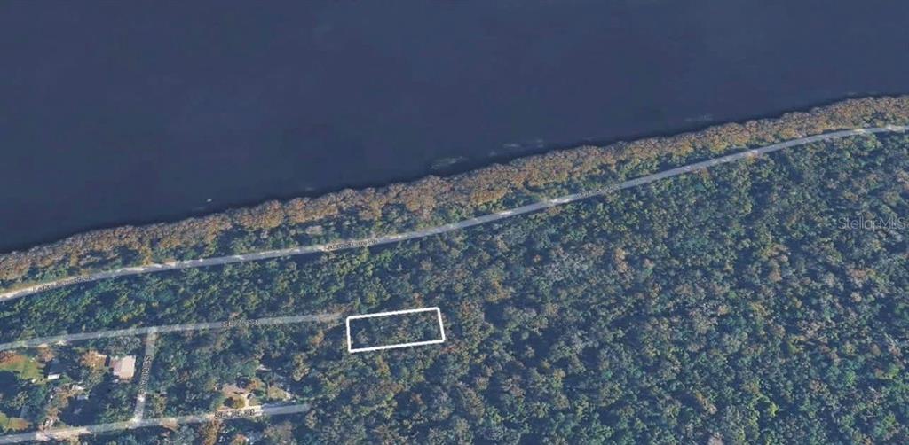 An aerial view shows a rectangular plot of land outlined in white within a wooded area — SE 75TH STREET, GAINESVILLE, FL