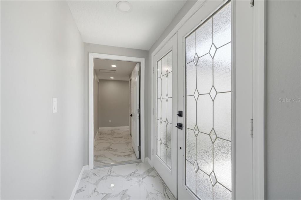 A bright entryway features white marble-look tile flooring and a double door with decorative glass — 6224 KELLER DRIVE UNIT 1, PORT RICHEY, FL
