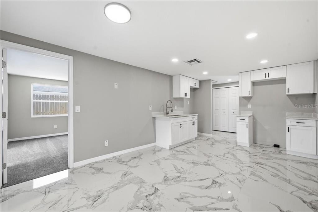 A kitchen with white cabinets, marble-patterned tile flooring, and a doorway leading to a bedroom — 6224 KELLER DRIVE UNIT 1, PORT RICHEY, FL