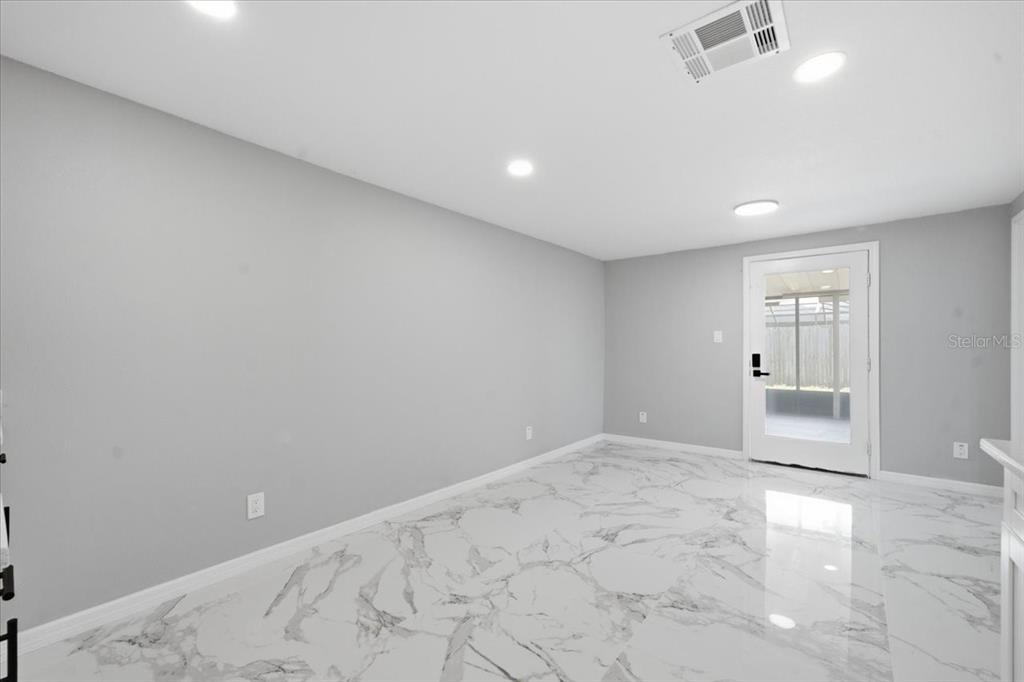 A room with light gray walls, white marble-patterned tile flooring, and a glass-paneled exterior door — 6224 KELLER DRIVE UNIT 1, PORT RICHEY, FL
