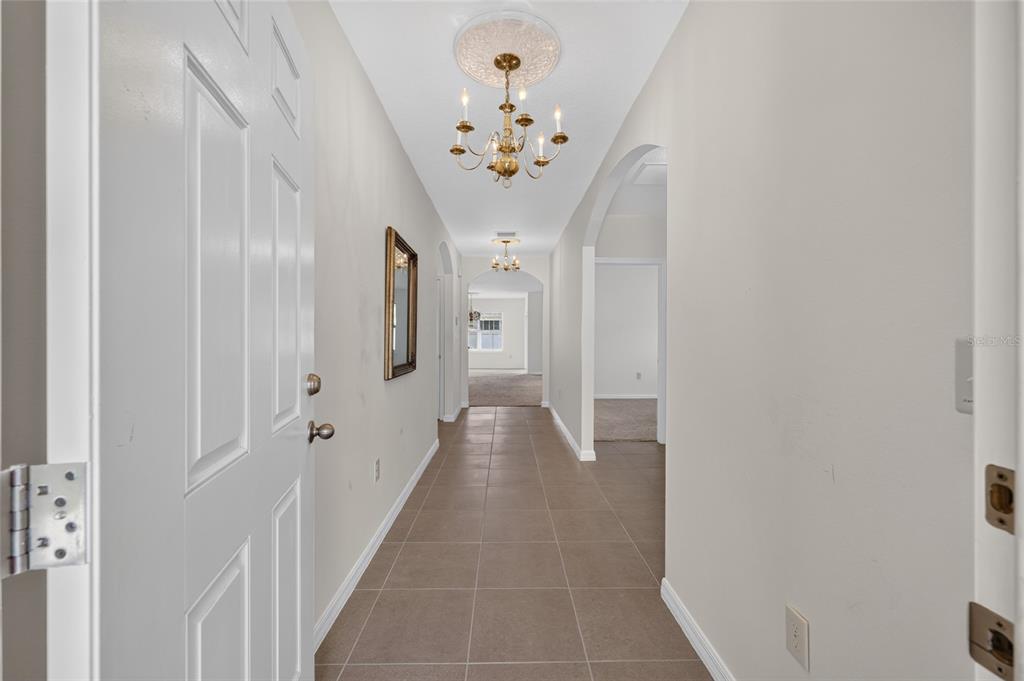 A tiled hallway leads from an open doorway toward a distant room with carpeted flooring — 3886 SE 97TH LANE, BELLEVIEW, FL