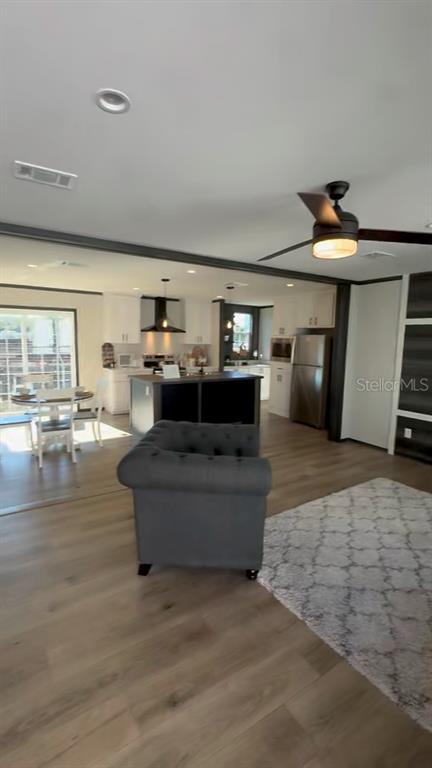 An open-concept living area features a grey armchair, a kitchen island, and light wood flooring — 17790 NW 266TH STREET, HIGH SPRINGS, FL
