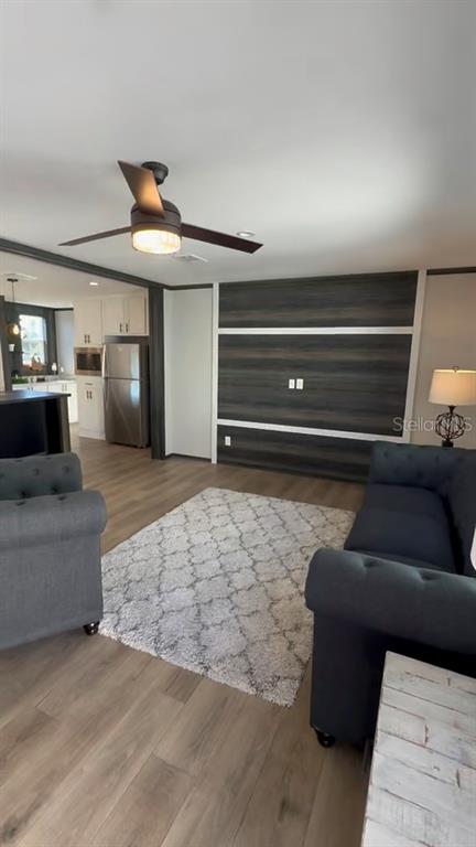 A living room features wood-look flooring, a dark wood accent wall, and a ceiling fan — 17790 NW 266TH STREET, HIGH SPRINGS, FL