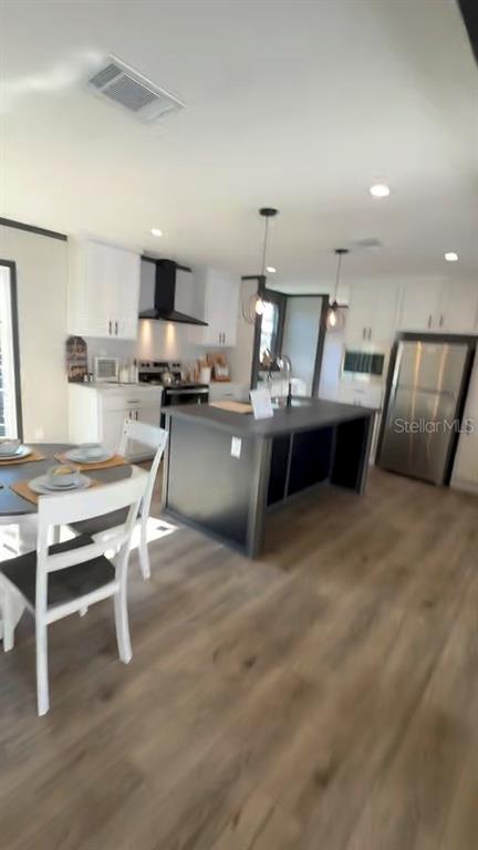 A kitchen features white cabinetry, a dark island, stainless steel appliances, and light wood flooring — 17790 NW 266TH STREET, HIGH SPRINGS, FL
