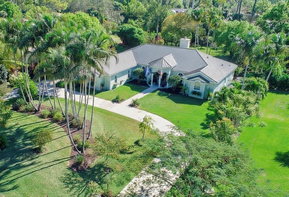 An aerial view of a single-story house with a metal roof and a curved driveway — 14921 Horseshoe Trace, Wellington FL 33414, WELLINGTON, FL