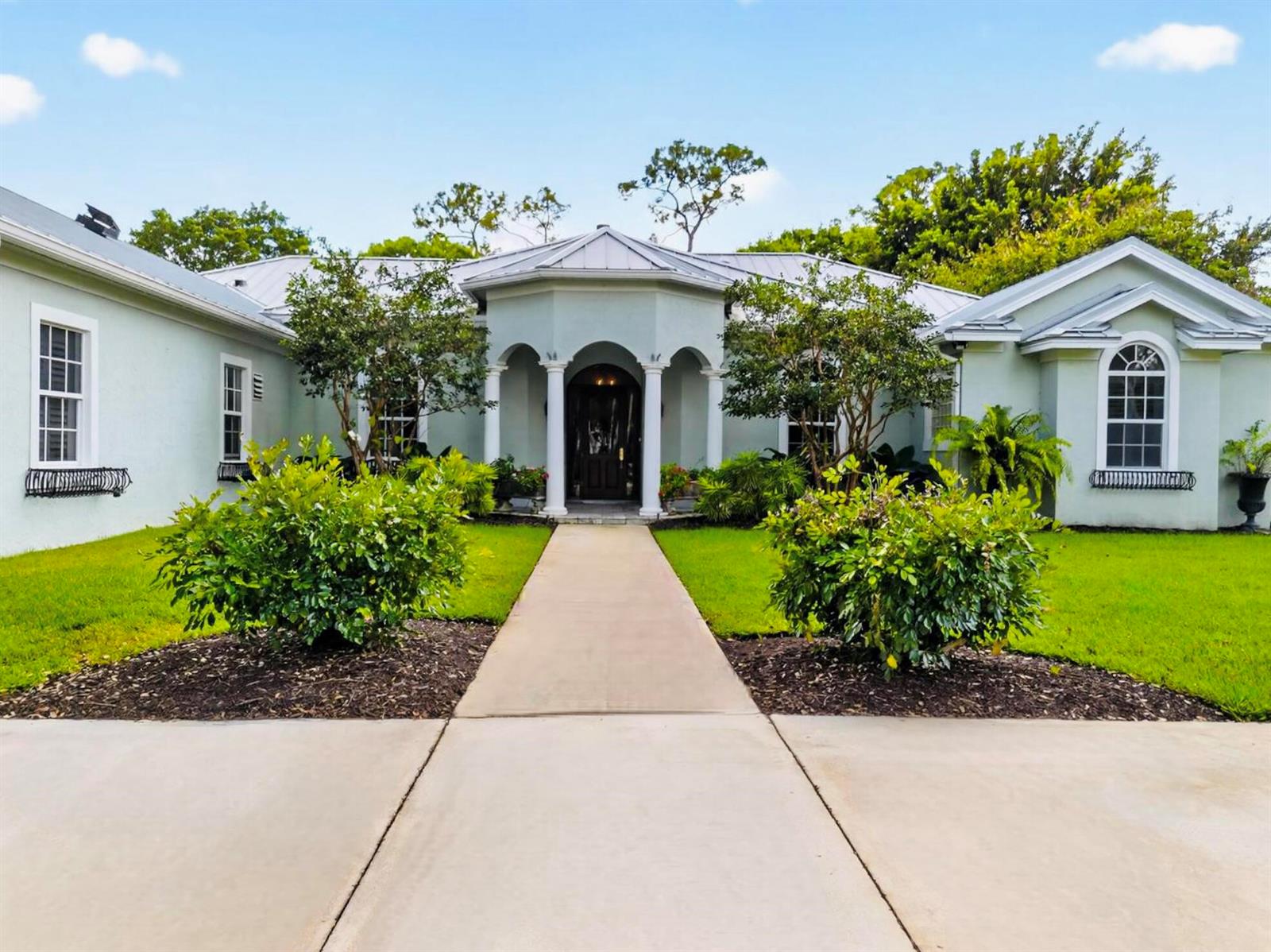 A light green single-story house features a central arched entryway with white columns — 14921 Horseshoe Trace, Wellington FL 33414, WELLINGTON, FL