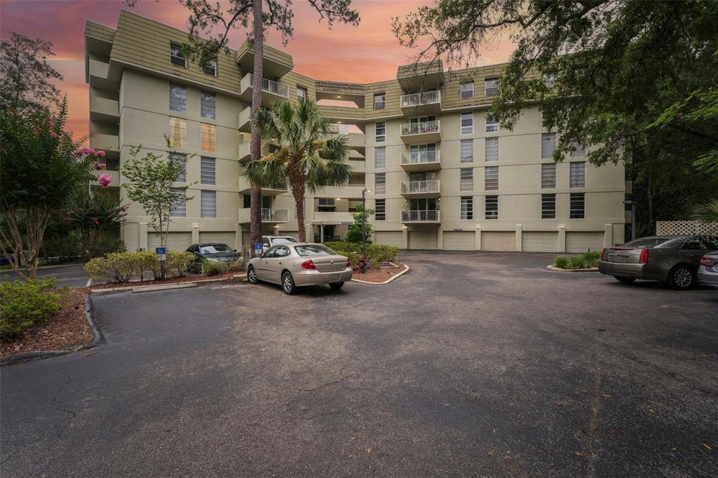 A multi-story apartment building with balconies and a parking lot in the foreground — 1717 NW 23RD AVENUE UNIT 4E, GAINESVILLE, FL