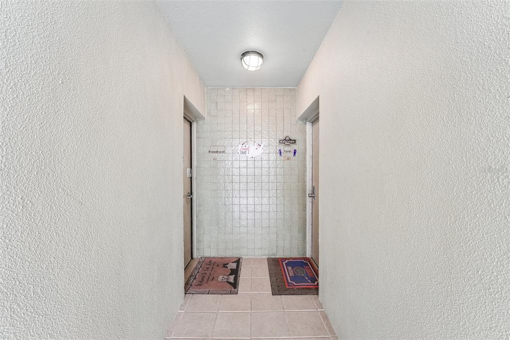 A tiled entryway features two doors, a central tiled wall, and two welcome mats — 1717 NW 23RD AVENUE UNIT 4E, GAINESVILLE, FL