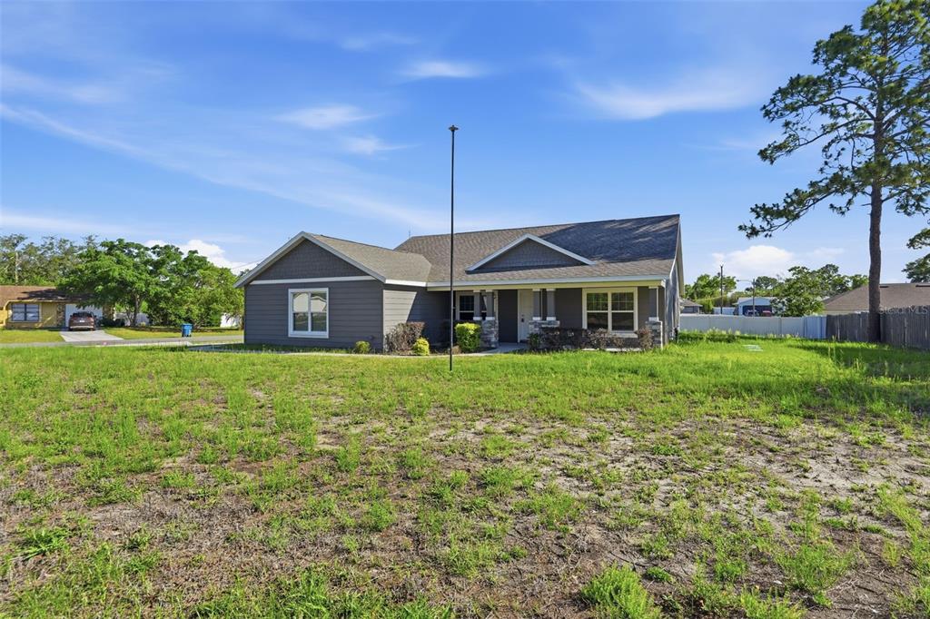 A gray single-story house with a gabled roof sits on a large, grassy lot — 5332 PIERPOINT AVENUE, SPRING HILL, FL