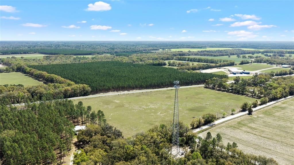 An aerial view shows a tall communication tower standing in a large, open grassy field — 300 NE 708 AVENUE, OLD TOWN, FL