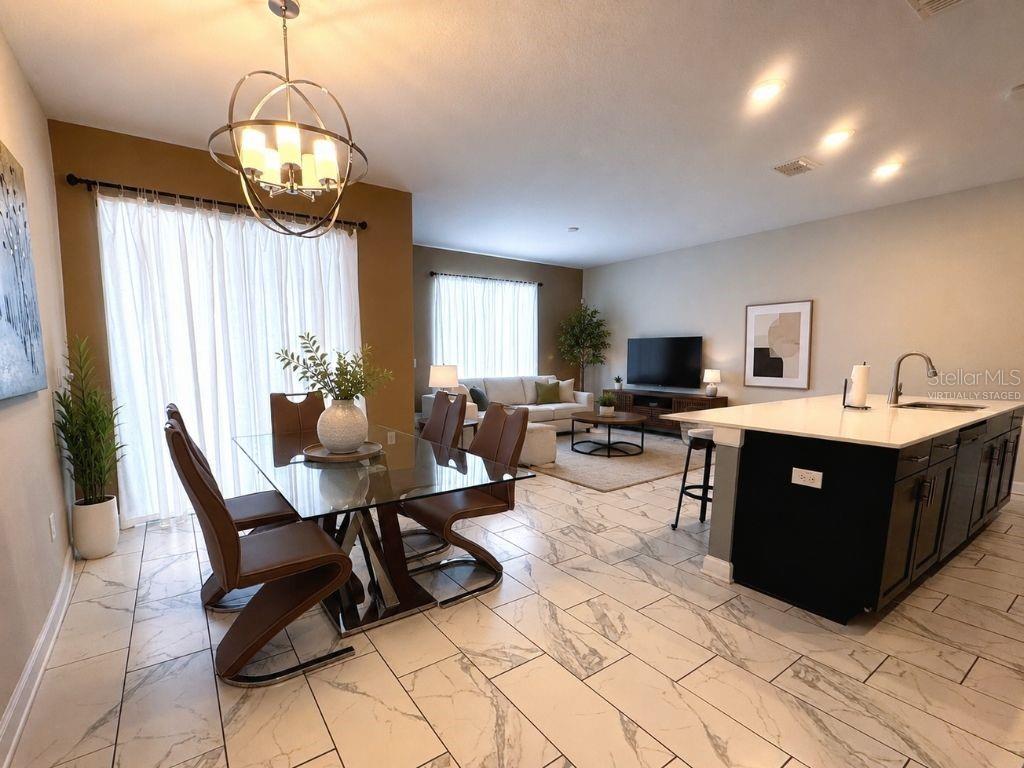 An open-concept kitchen and dining area features white marble-look tile flooring and a glass table — 1555 SANDBAGGER DRIVE, DAVENPORT, FL