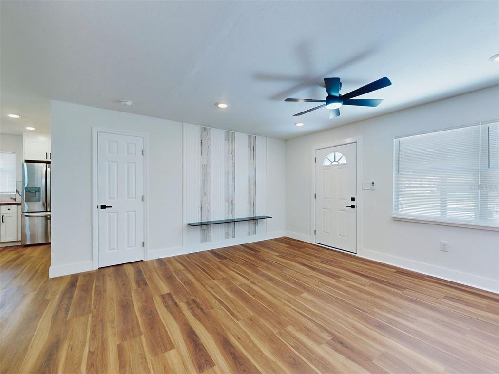 A living room features wood-look flooring, a ceiling fan, and a decorative wall accent — 410 INWOOD AVENUE, NEW SMYRNA BEACH, FL