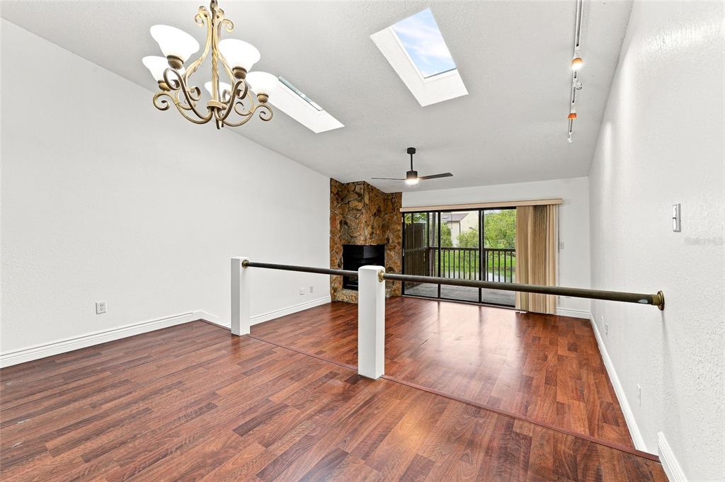 A sunken living room features a stone fireplace, dark wood flooring, and a sliding glass door — 6435 92ND PLACE N UNIT 902, PINELLAS PARK, FL