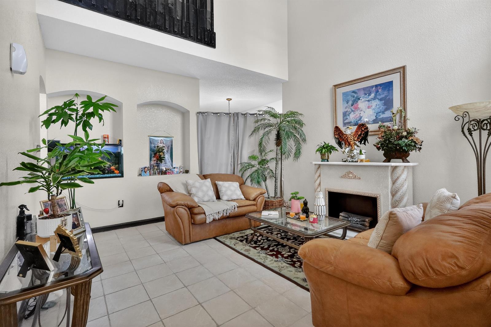 A living room features a fireplace, two brown sofas, tile flooring, and high ceilings — 16266 SW 103rd Terrace, Miami FL 33196, MIAMI, FL