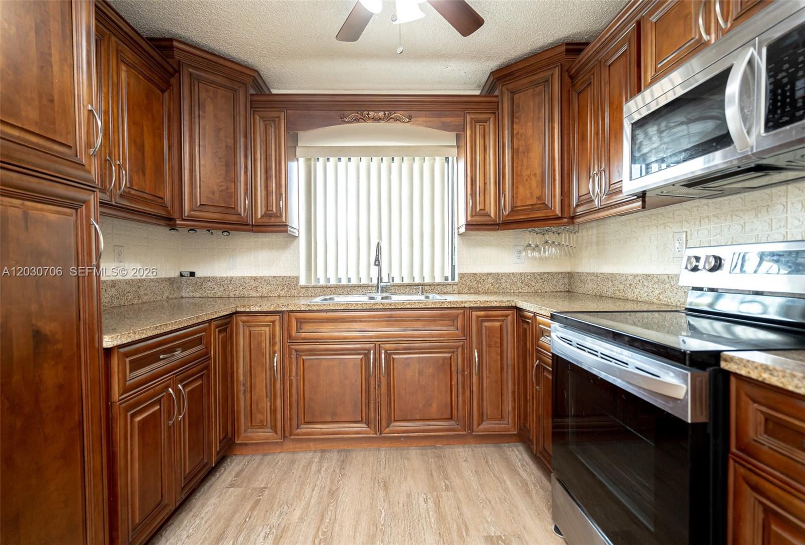 A kitchen features dark wood cabinets, granite countertops, and stainless steel appliances — 2740 W 62nd Pl # 201, Hialeah FL 33016, HIALEAH, FL