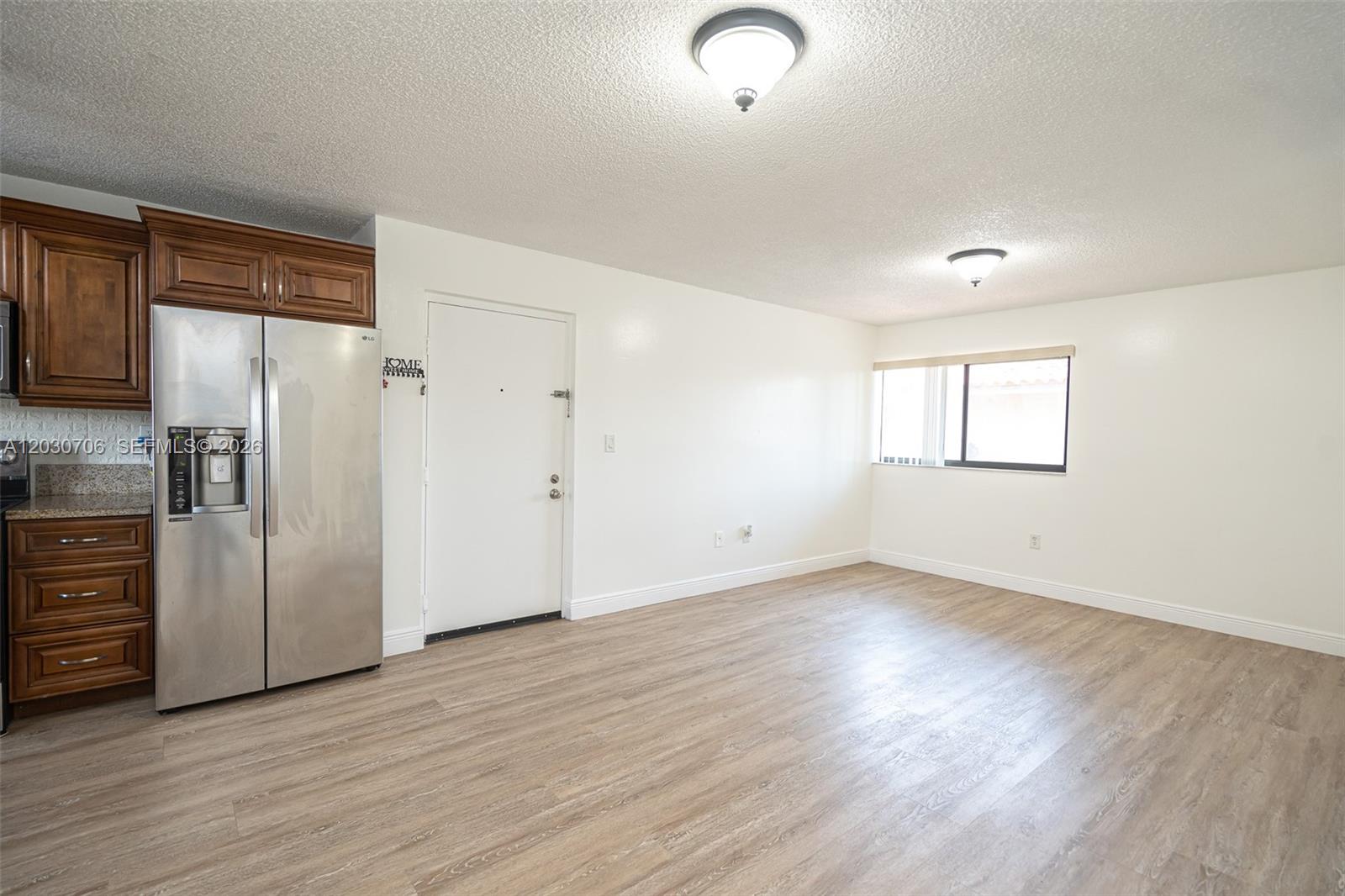 A kitchen area with wood cabinets and stainless steel appliances opens into a living space — 2740 W 62nd Pl # 201, Hialeah FL 33016, HIALEAH, FL